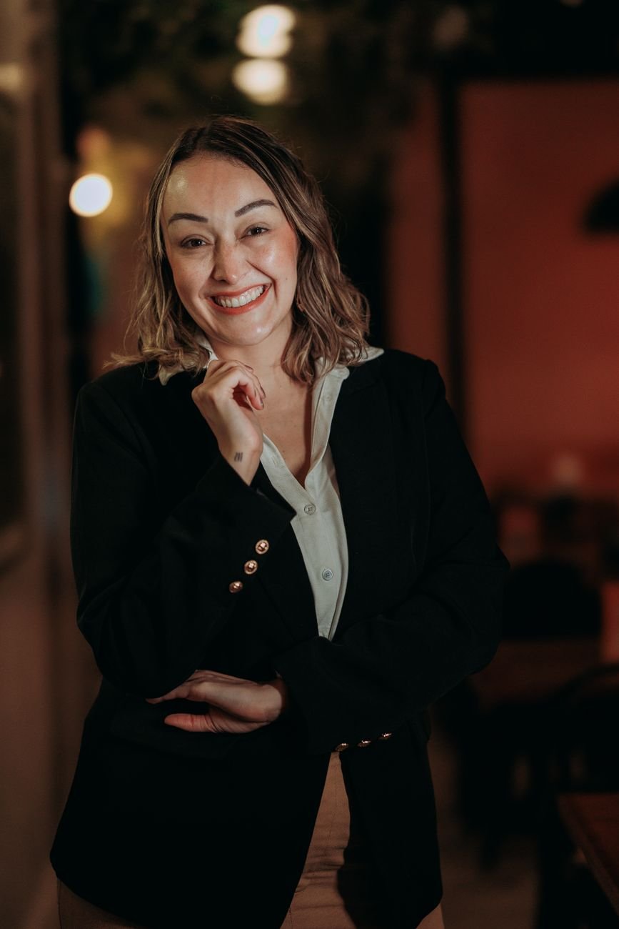 Professional woman in a business suit smiling warmly indoors with a blurred background.
