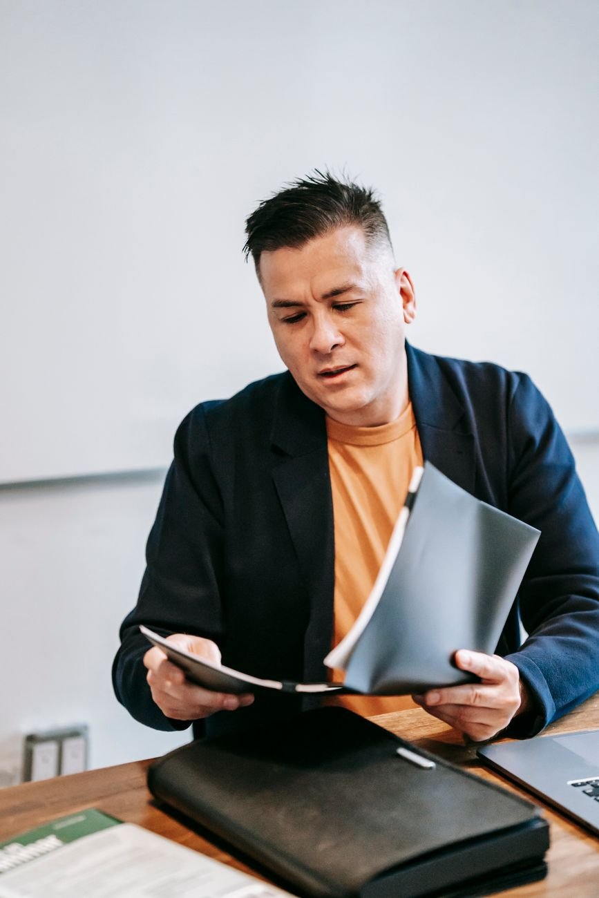 Businessman in a suit reviewing documents at an office desk, focused on work.